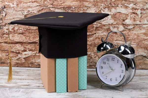 Composition of graduate objects. Composition of graduate hat, books and alarm clock.
